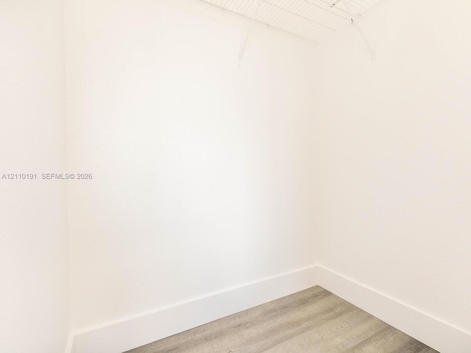 Walk-in closet featuring neutral walls, wood-finish flooring, and white wire shelving