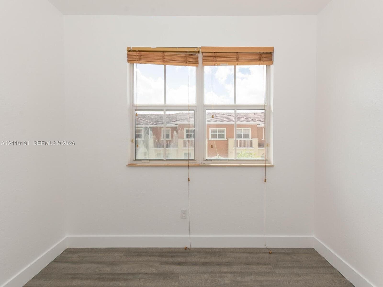 Neutral wall tones paired with gray wood-finish flooring and double-hung window featuring built-in wood-slat blinds