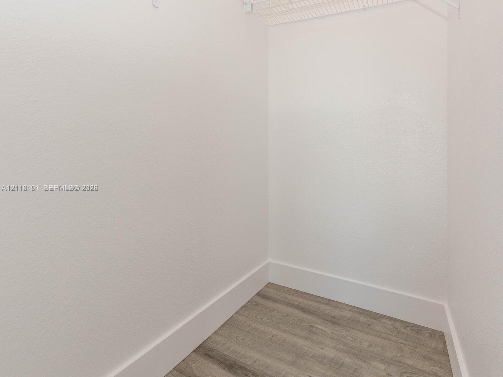 Storage space featuring neutral wall finishes and wood-finish flooring with installed wire shelving