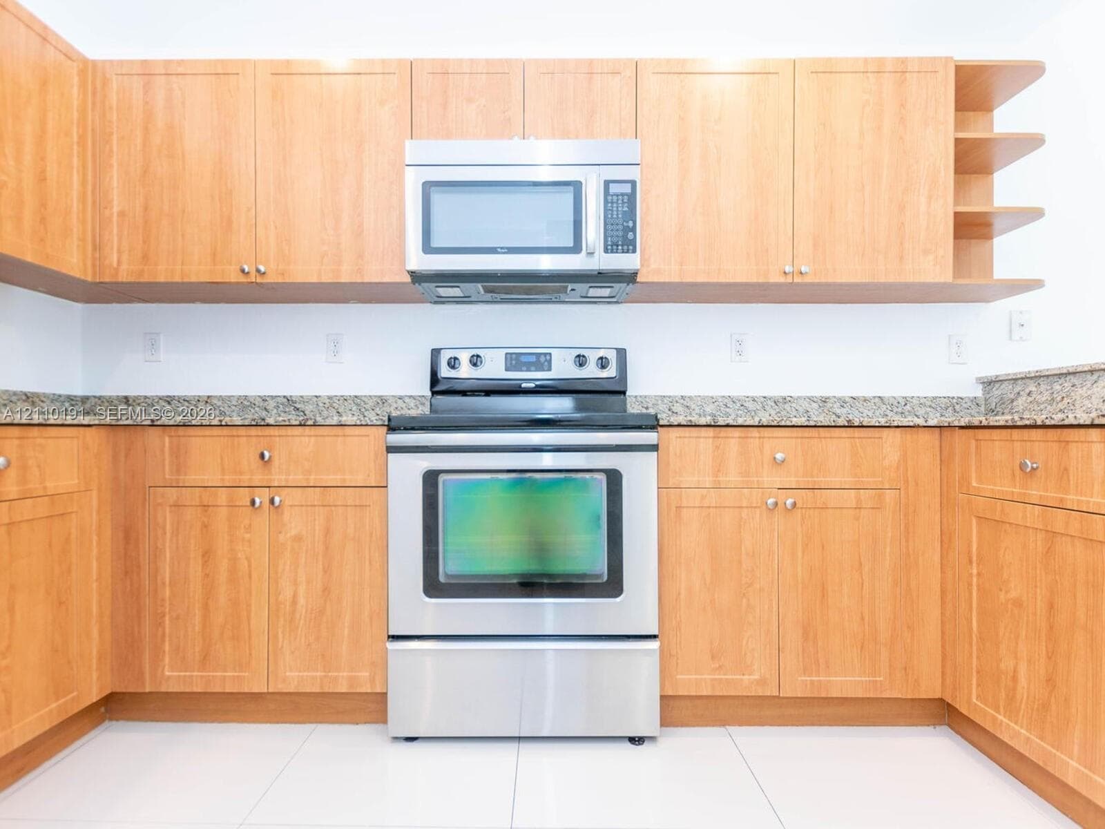 Kitchen featuring natural wood-finish cabinetry, stone-style countertops, stainless steel microwave, stainless steel range, and open-shelf storage