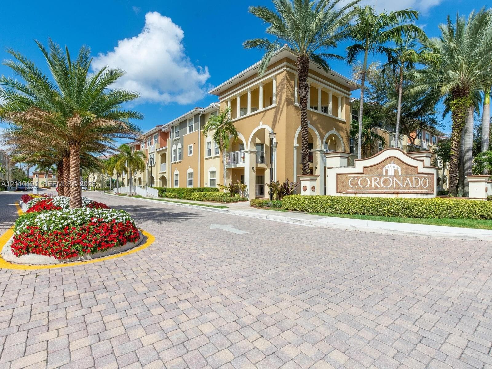 Exterior facade featuring architectural archways, multi-story balconies, paver driveway, mature palm trees, and manicured landscaping