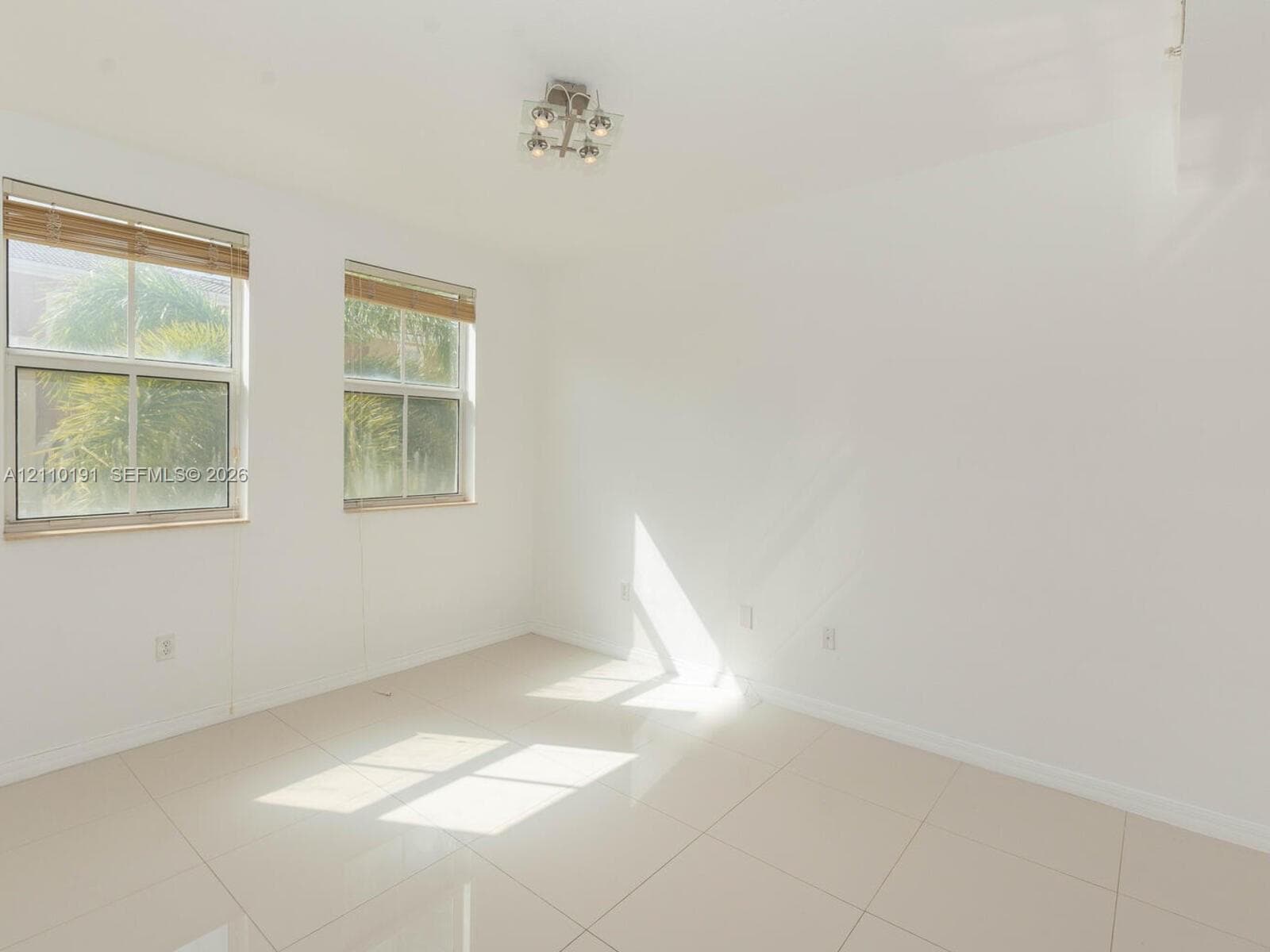 Neutral-toned tile flooring, dual double-hung windows with integrated blinds, and a multi-light flush-mount ceiling fixture