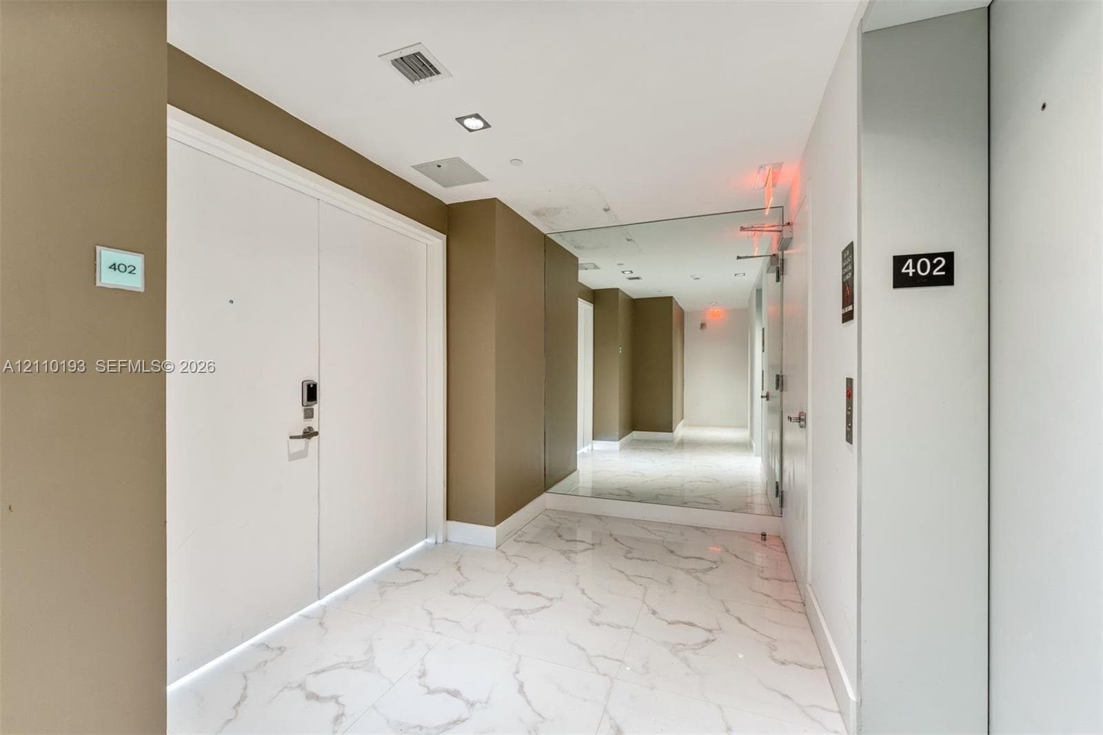 Entryway featuring polished stone-finish tile flooring, recessed ceiling lighting, and floor-to-ceiling mirror paneling