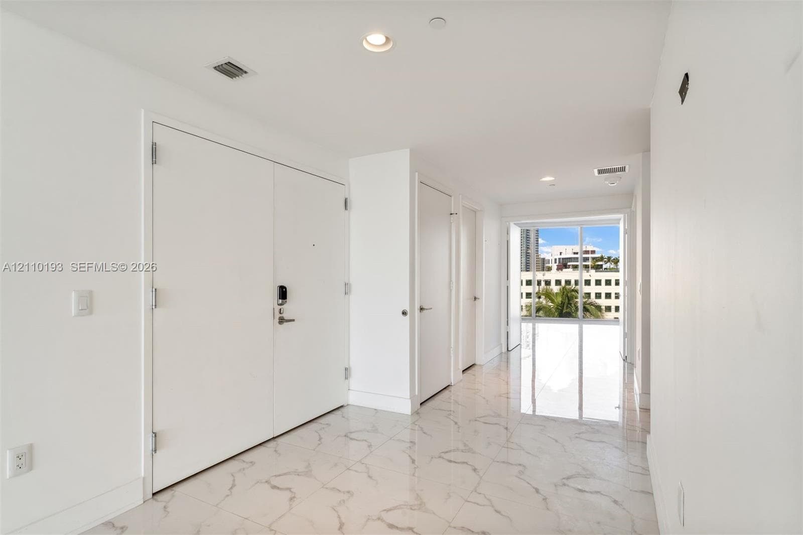 Interior space featuring white stone-finish tile flooring, recessed ceiling lighting, and floor-to-ceiling glass panel windows