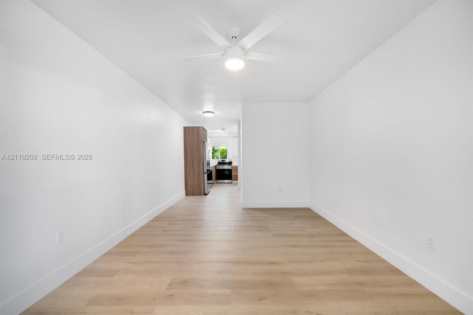 Interior space featuring wood-finish flooring, a contemporary white ceiling fan with integrated lighting, and flush-mount ceiling fixtures
