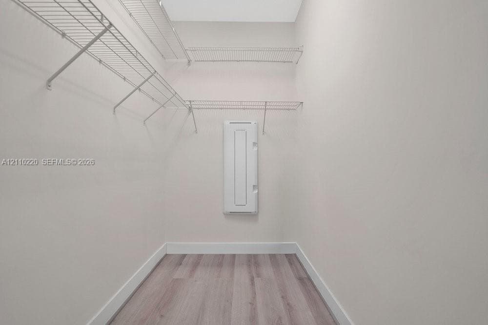 Storage space featuring tiered wire shelving and wood-finish flooring