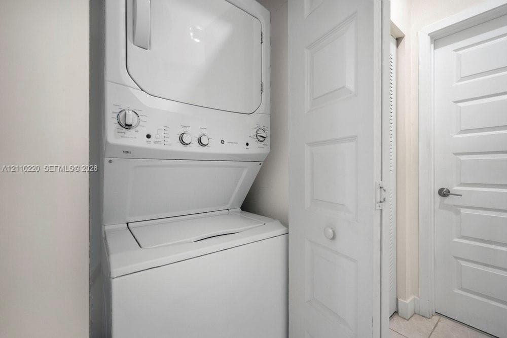 Stacked washer and dryer unit, louvered bi-fold closet doors, and solid-core paneled interior door