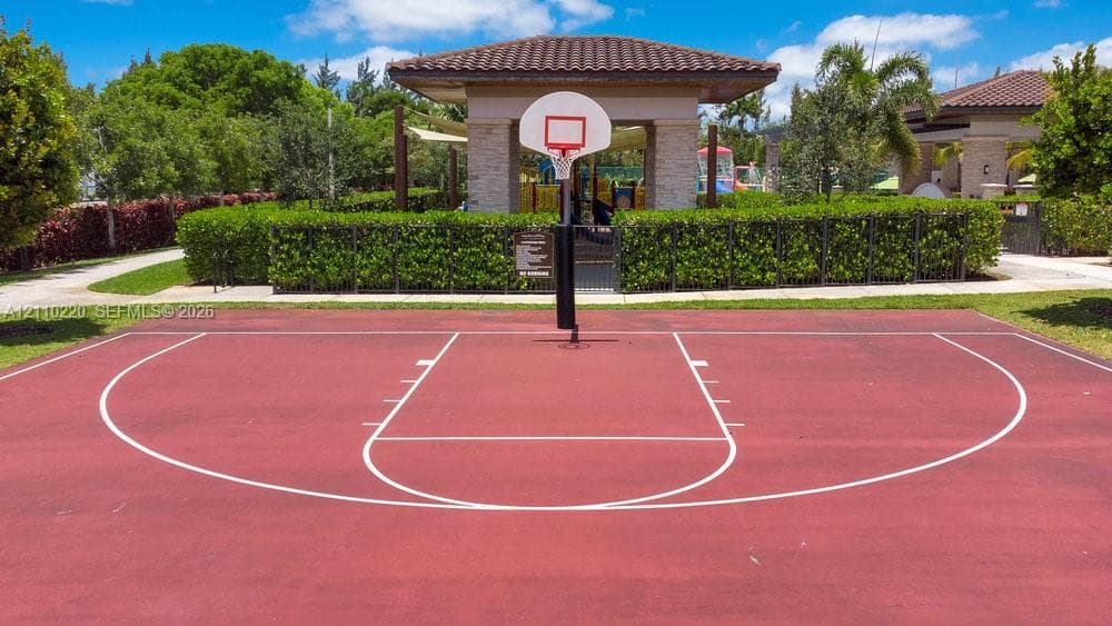 Outdoor basketball court featuring a paved surface, built-in hoop, and manicured landscaping