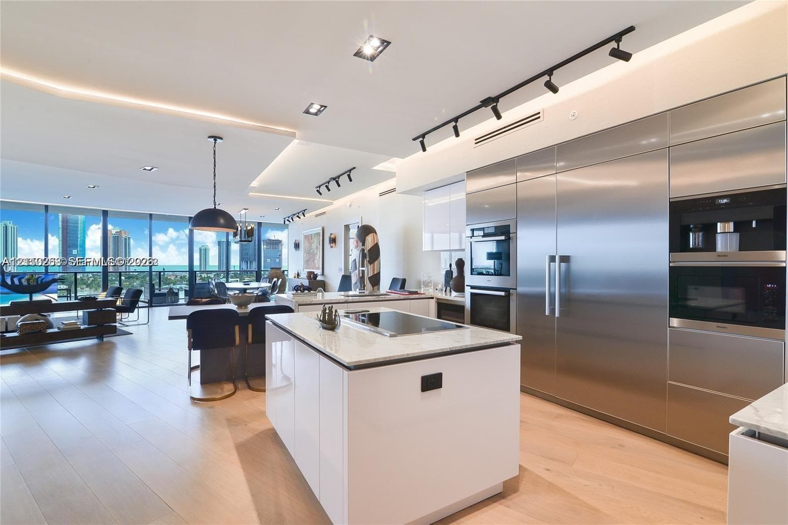 Kitchen featuring a center island with a stone countertop and integrated cooktop, stainless steel built-in appliances, high-gloss cabinetry, recessed ceiling lighting, and wood-finish flooring