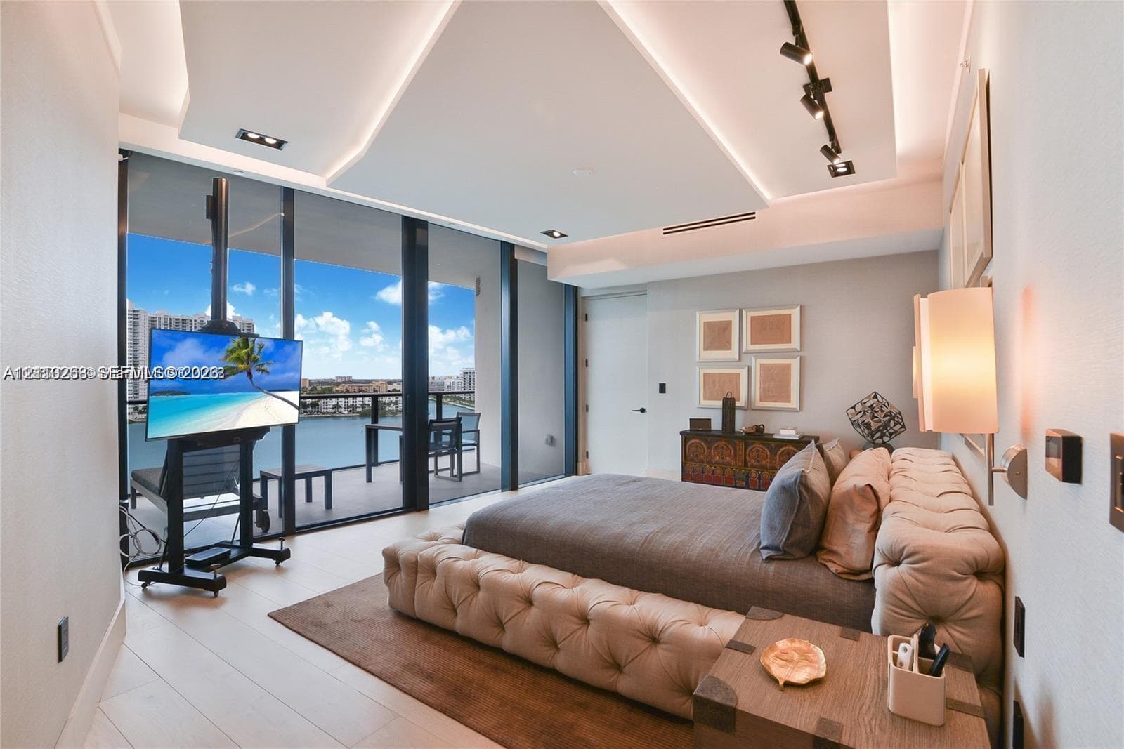 Floor-to-ceiling glass wall, recessed tray ceiling with accent lighting, track lighting, and a private balcony