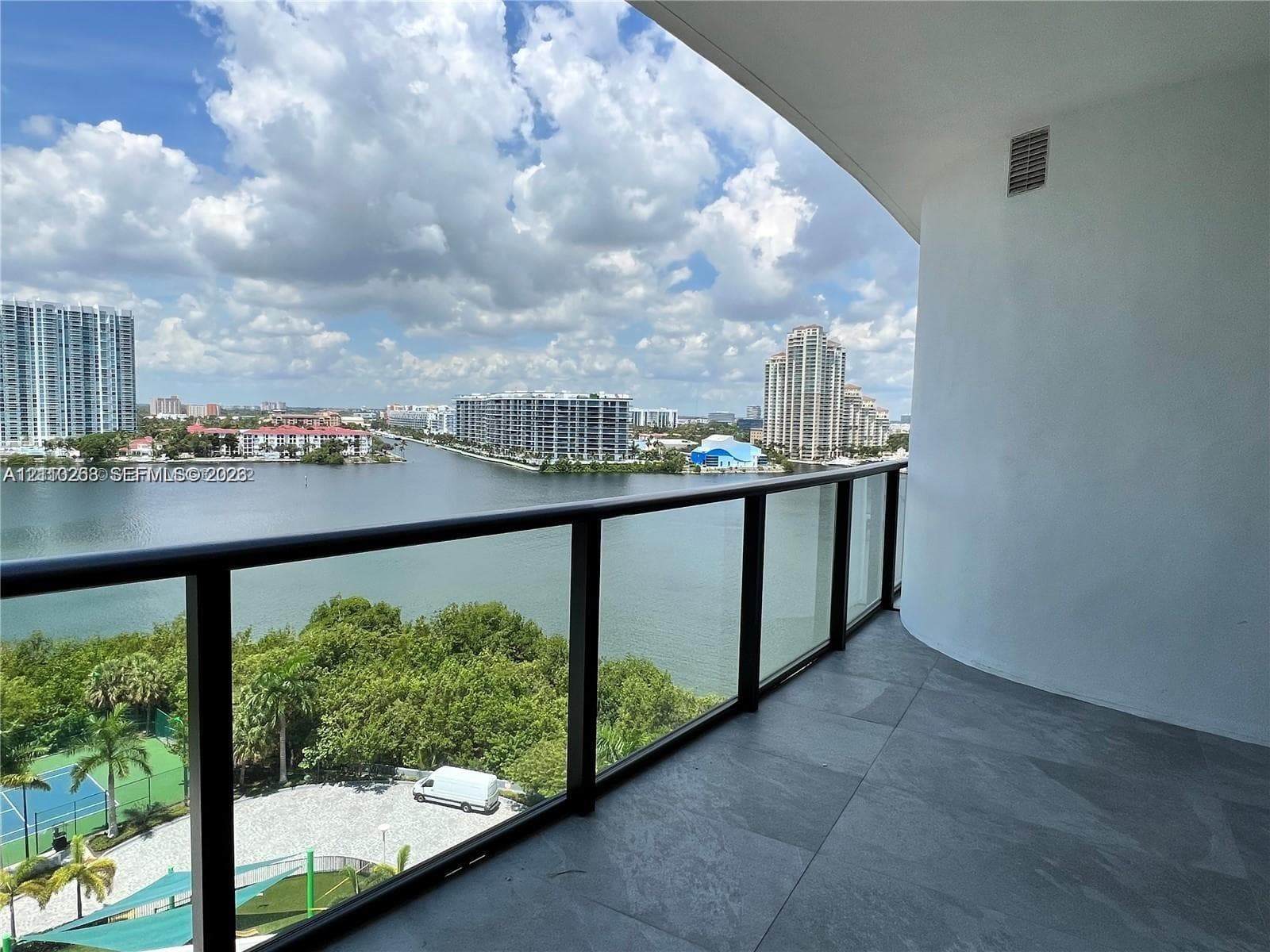 Covered balcony featuring large-format tile flooring and a glass-paneled railing