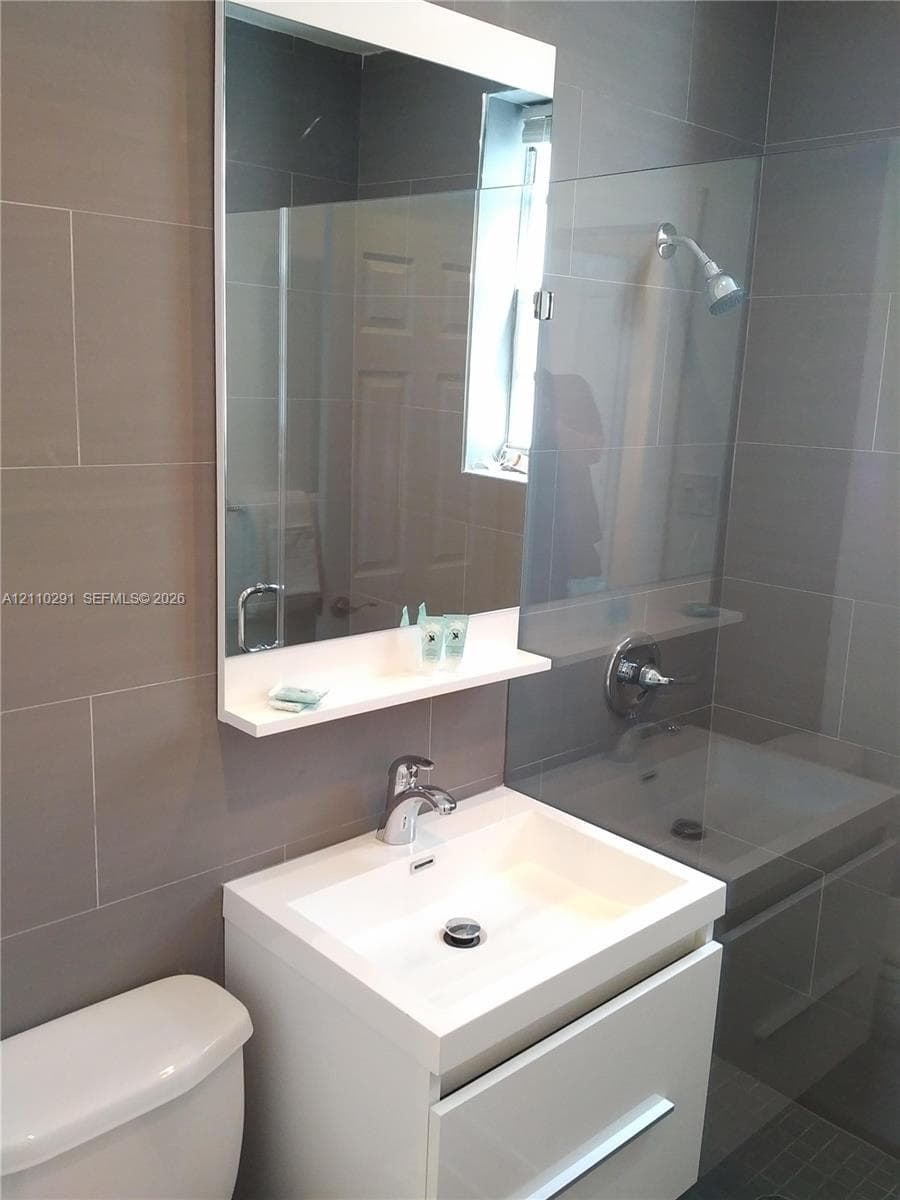 Modern wall-mounted vanity featuring a square vessel sink, polished chrome faucet, and rectangular mirror with an integrated shelf