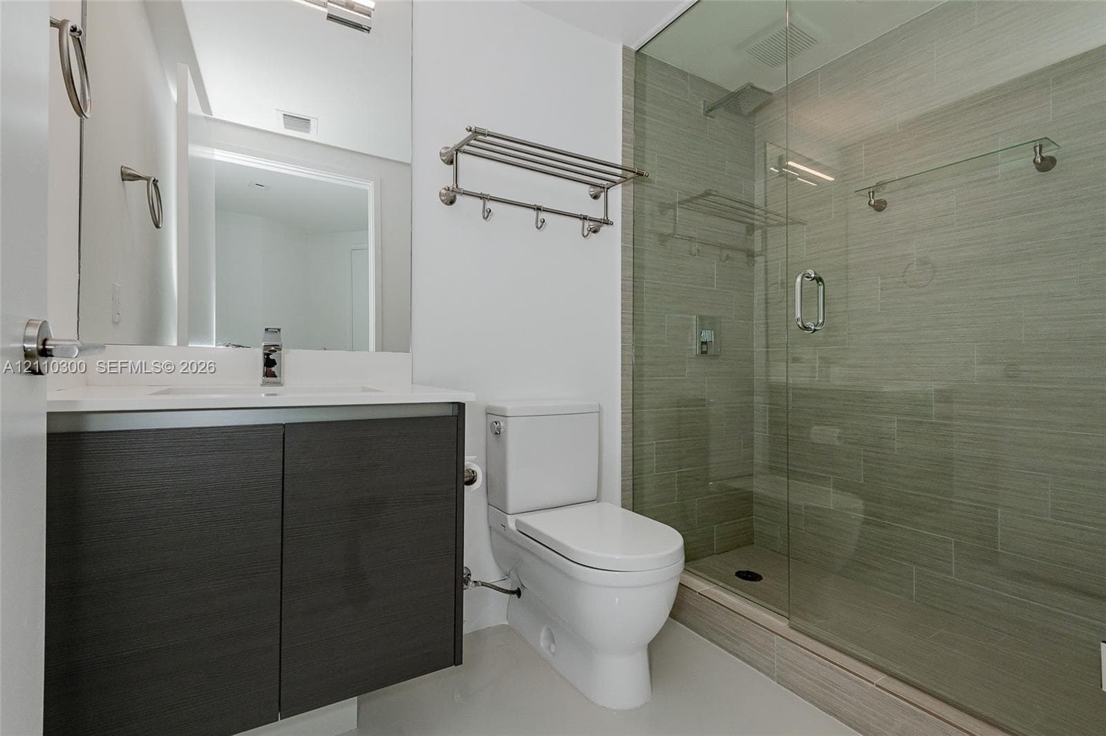 Laundry area featuring custom white upper cabinetry, stainless steel-trimmed appliances, and smooth-finish flooring