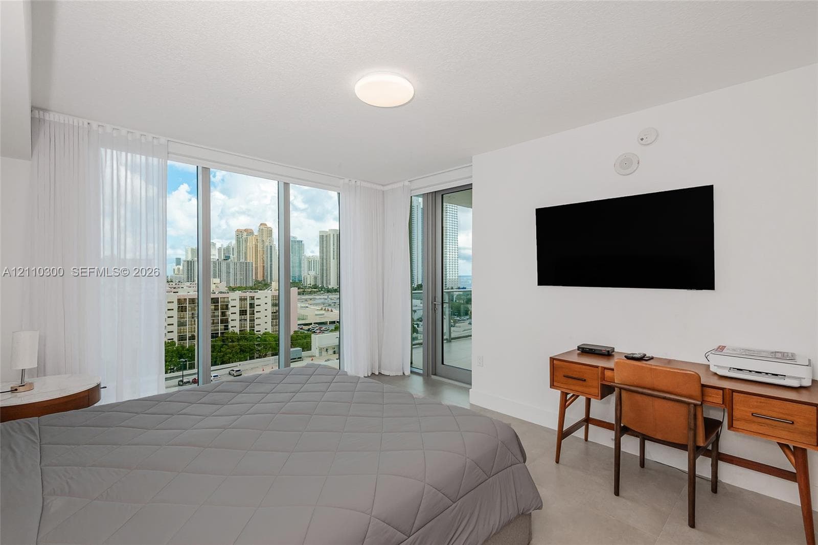Master Bedroom. Neutral-toned tile flooring, large sliding glass door with access to a balcony, and dual bi-fold closet doors