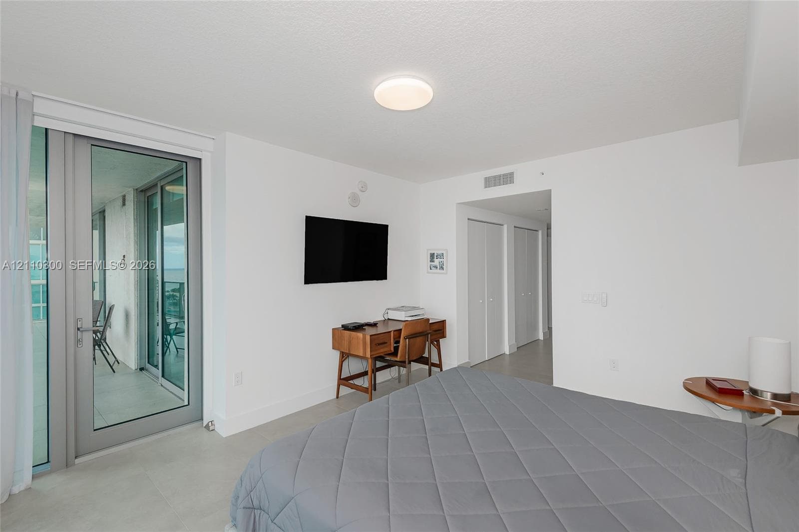 Master Bedroom. Neutral-toned large-format tile flooring, high ceilings, and recessed overhead lighting