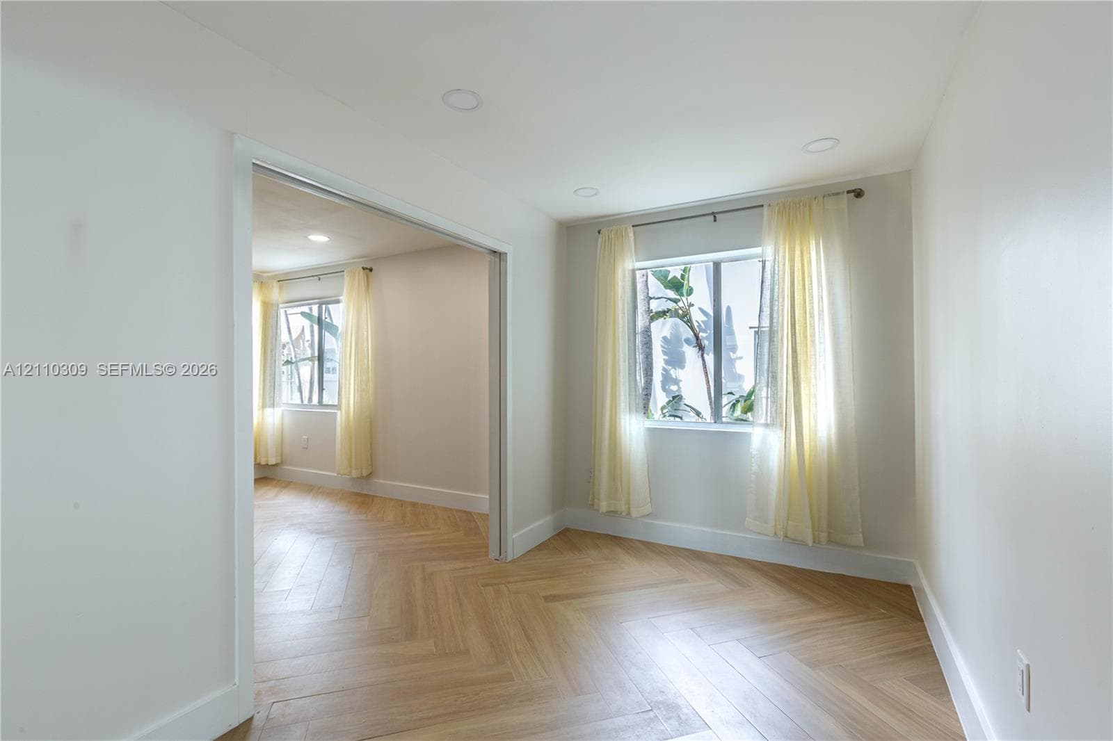 Herringbone pattern wood-finish flooring, recessed lighting, and dual windows