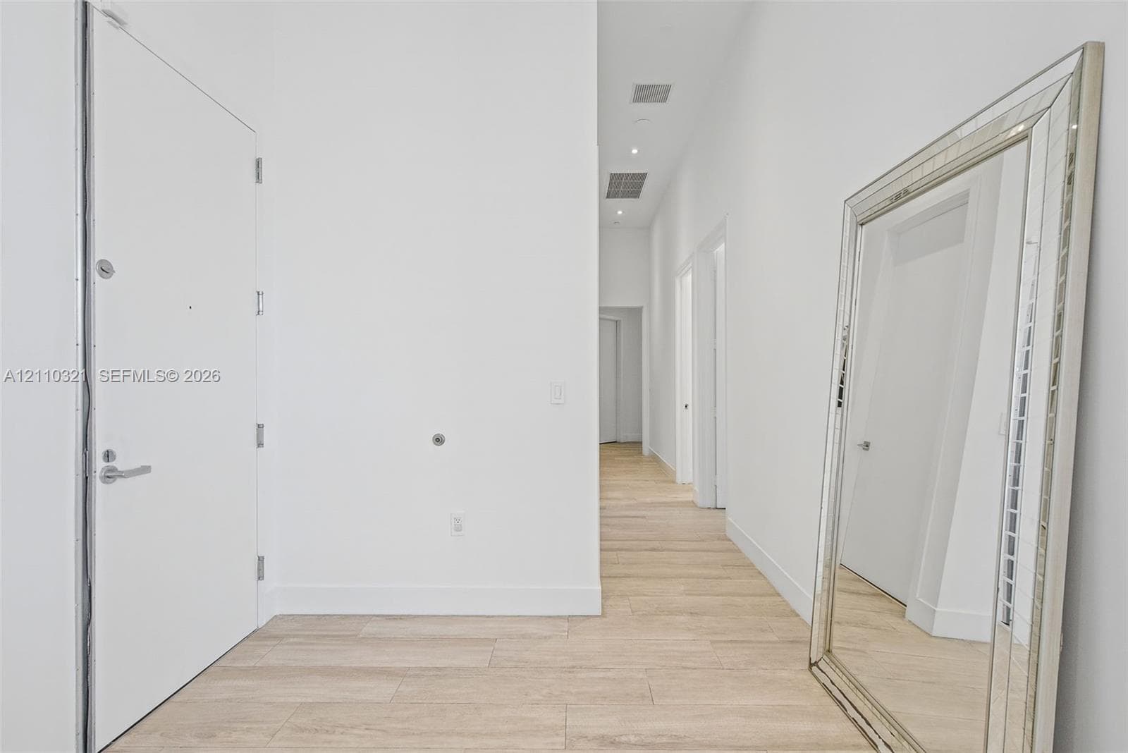 High ceilings featuring recessed lighting, wood-finish flooring, and minimalist interior doors