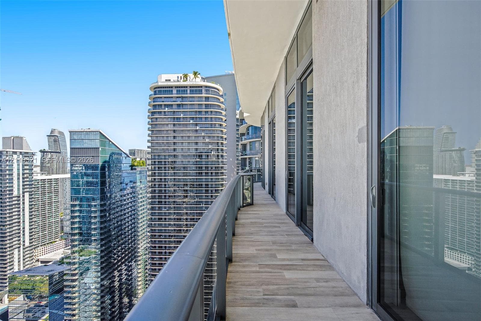 Covered balcony featuring wood-finish flooring, metal railing, and floor-to-ceiling glass sliding doors