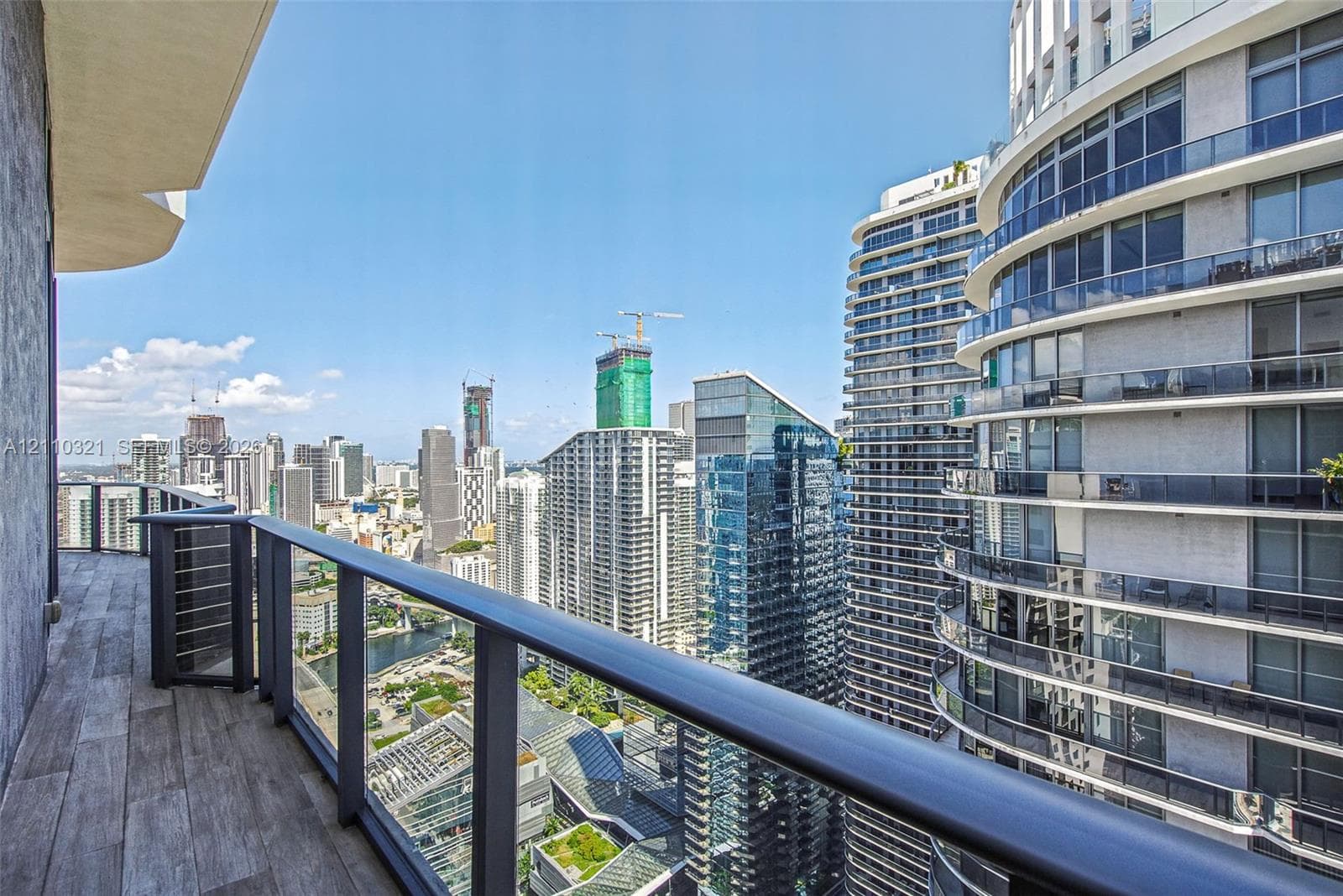 Covered balcony featuring wood-finish flooring and a metal railing with horizontal bars