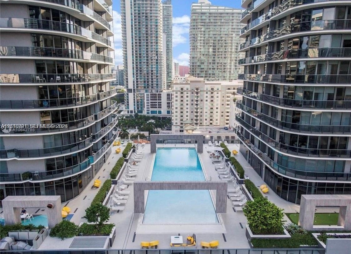High-rise terrace featuring an outdoor swimming pool, stone-finish architectural frames, paved deck area, and manicured landscaping