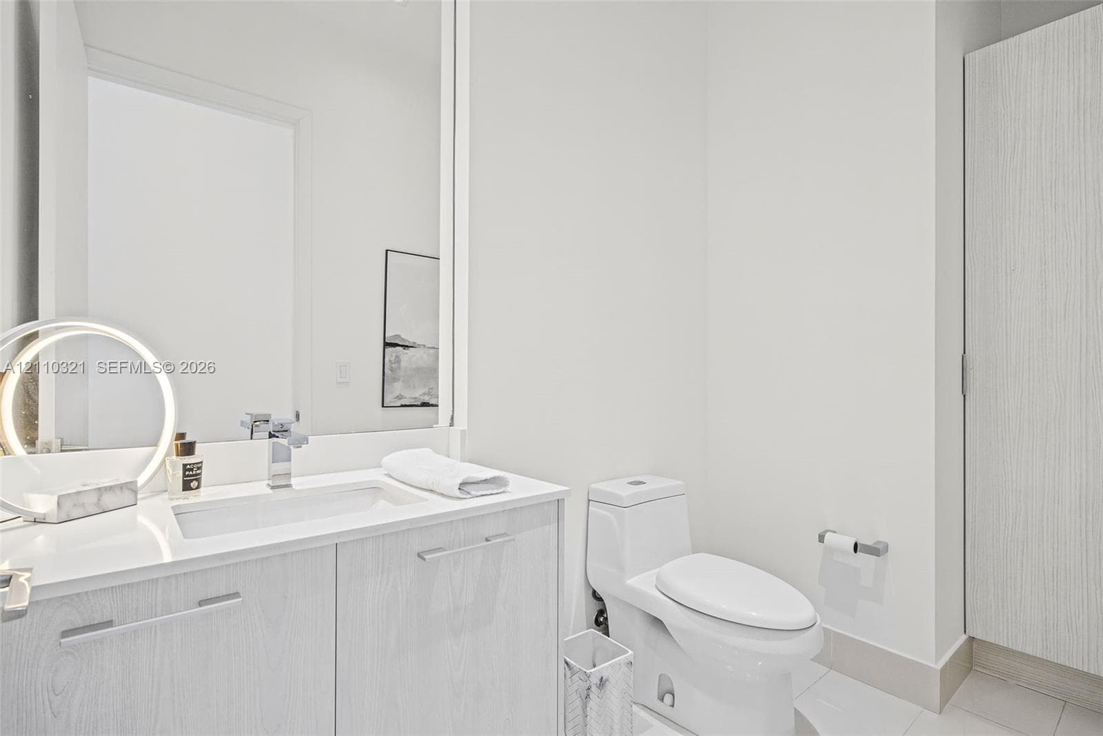 Vanity featuring a stone-surface countertop, integrated rectangular basin, chrome faucet, and wood-grain cabinetry, paired with a high-profile one-piece toilet and a full-height wall mirror