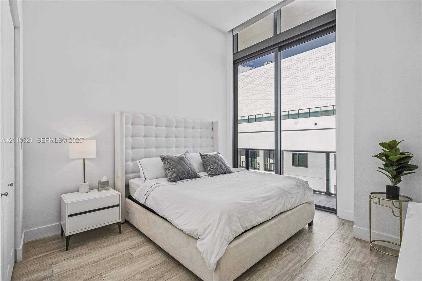 Floor-to-ceiling windows with integrated transom, wood-finish tile flooring, and neutral wall palette