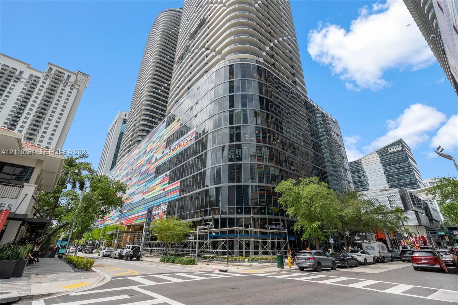 High-rise building featuring a glass curtain wall, integrated curved architectural elements, multi-story facade, and exterior decorative murals