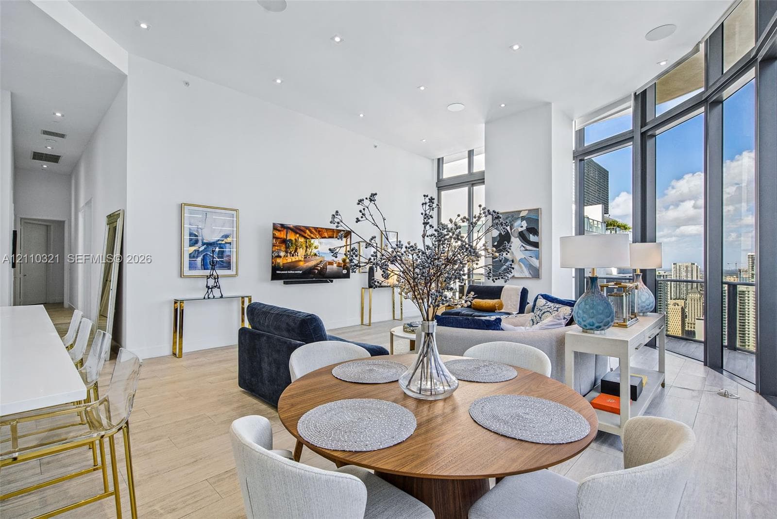 Expansive floor-to-ceiling windows, wood-finish tile flooring, recessed ceiling lighting, and soaring high ceilings