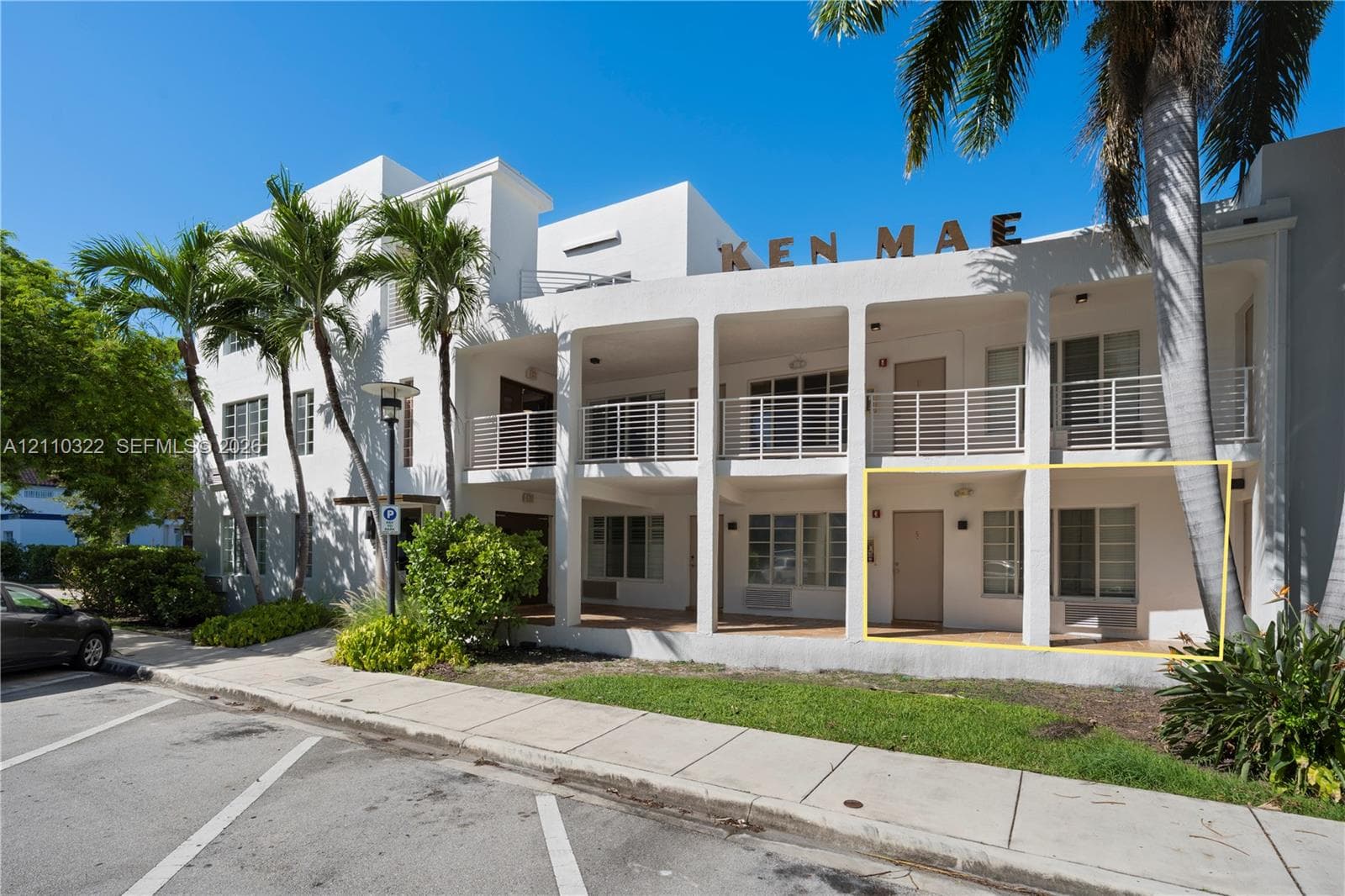 Multi-story building facade with stucco exterior, ground-level covered patio, and metal railings