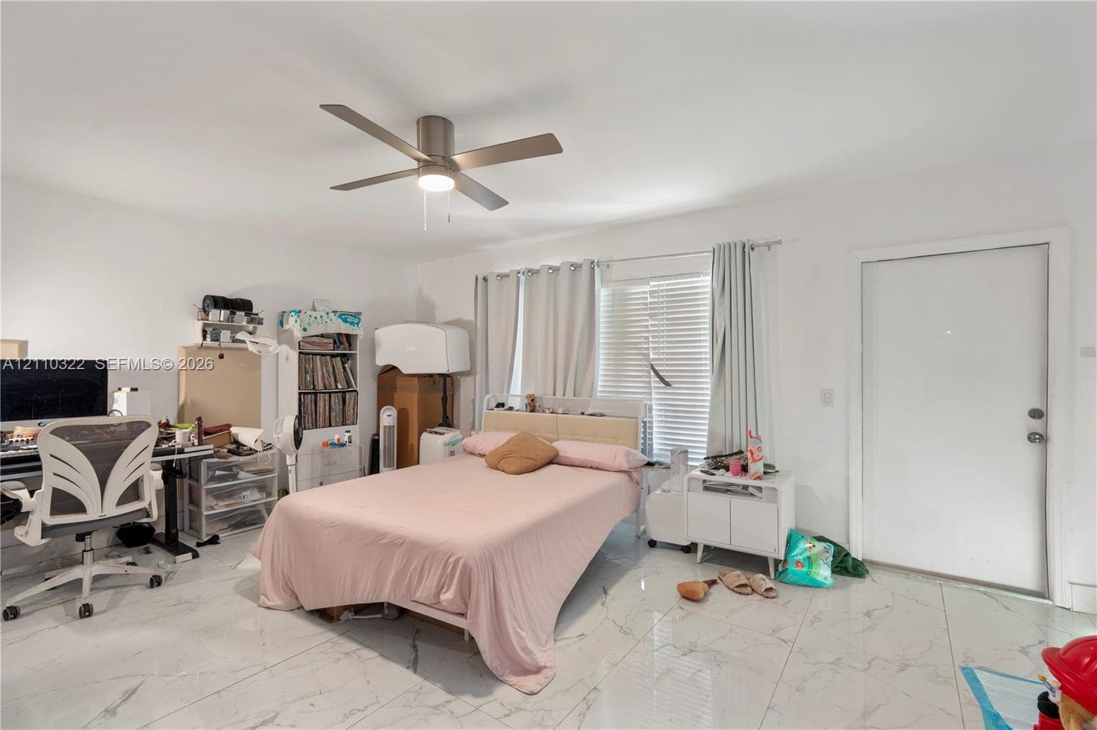 Large-format light-toned tile flooring, neutral walls, and a multi-blade ceiling fan with an integrated light fixture