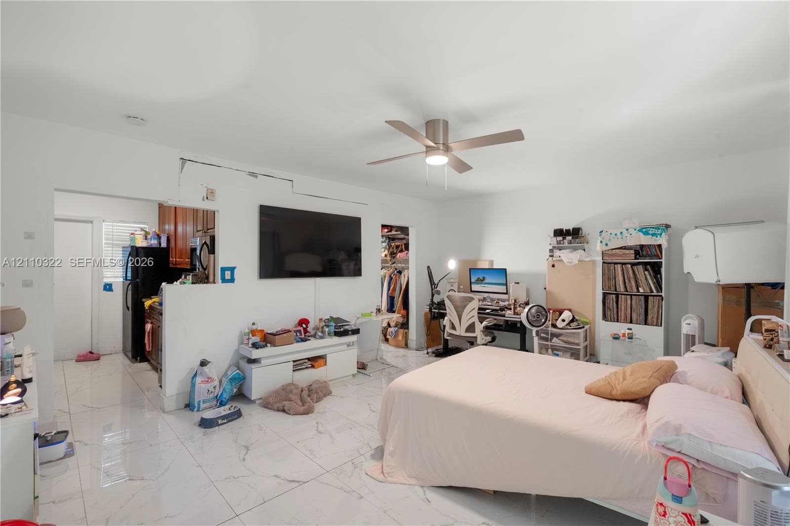 Large-format white tile flooring with grey veining, neutral wall palette, and ceiling-mounted light fixture with integrated fan