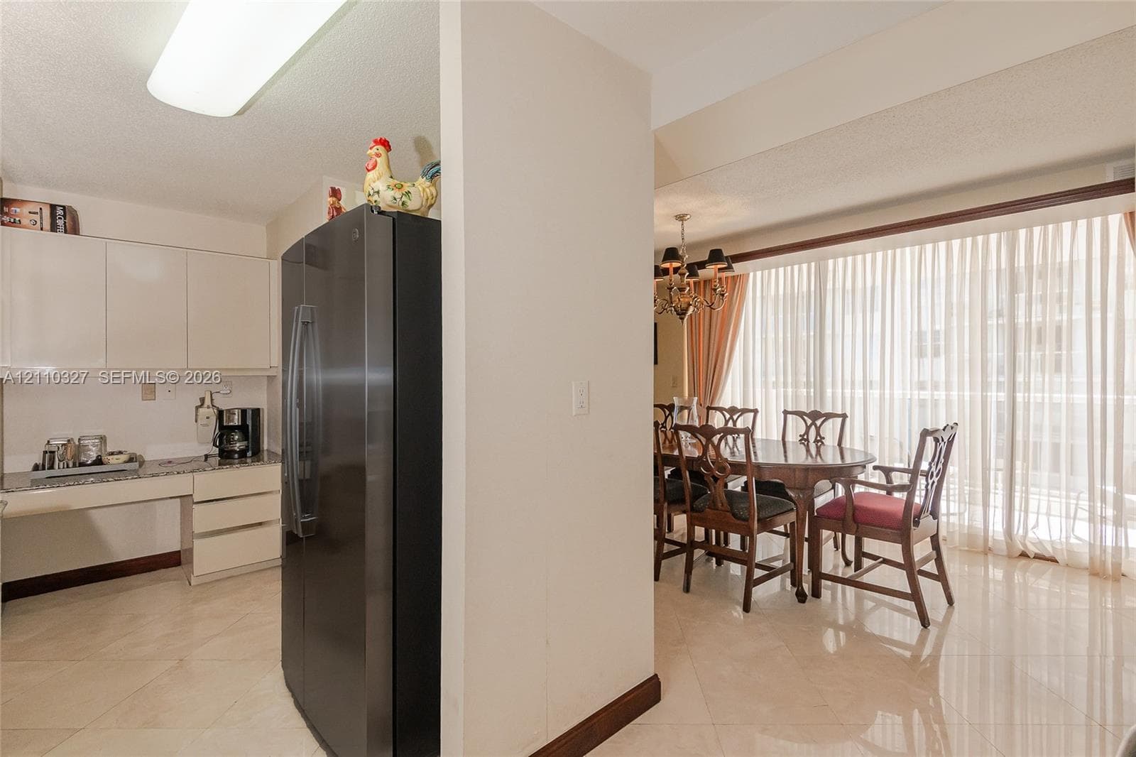 Kitchen featuring flat-panel cabinetry, light-toned stone countertops, a dark-finish double-door refrigerator, and polished stone tile flooring throughout