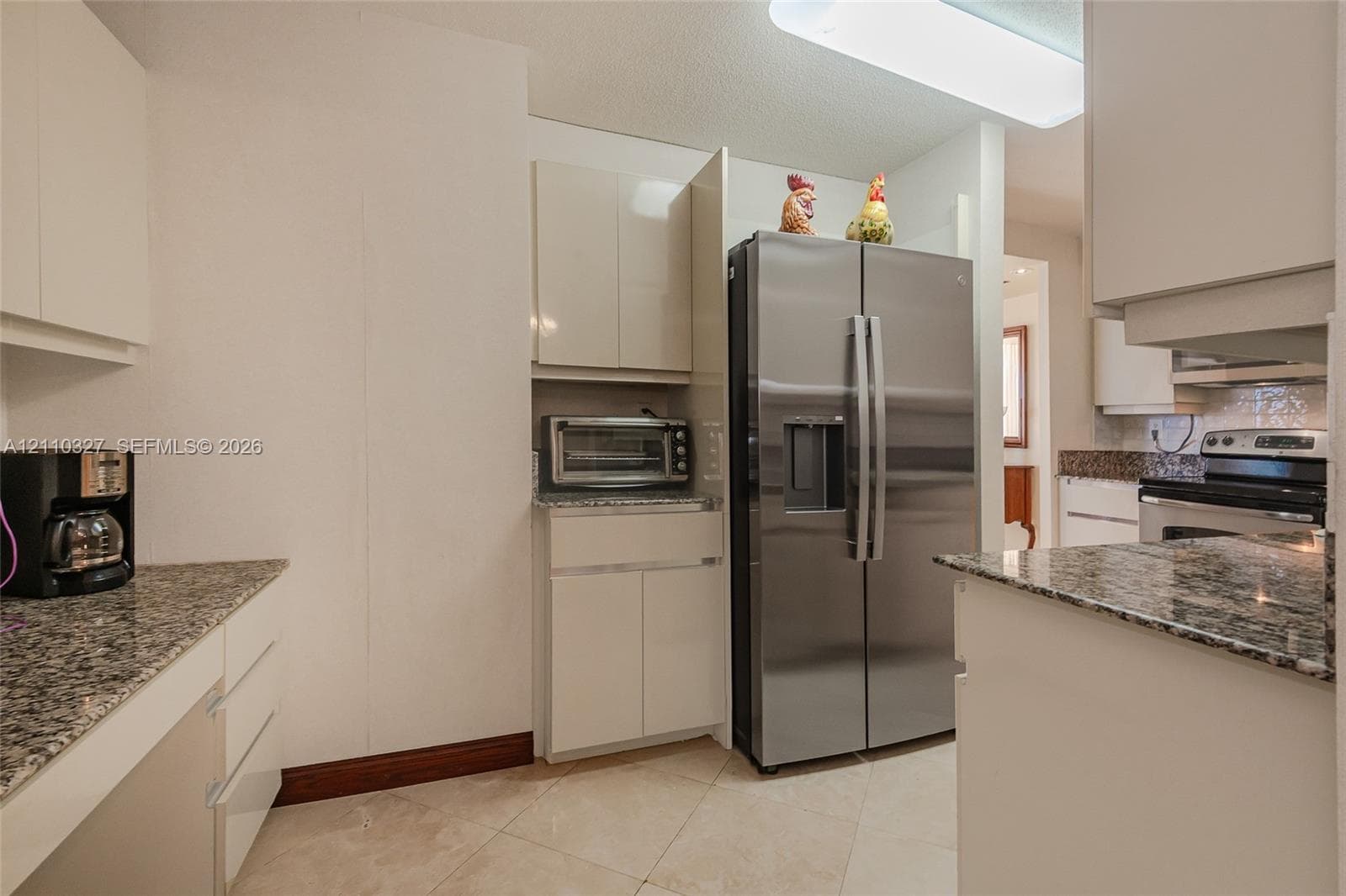Kitchen featuring flat-panel cabinetry, stone countertops, stainless steel side-by-side refrigerator, recessed lighting, and tile flooring