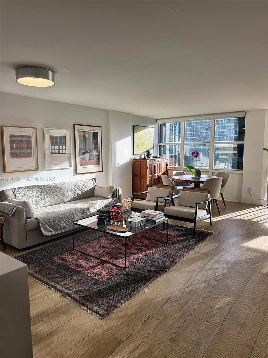 Living area featuring wood-finish flooring, floor-to-ceiling windows, and a flush-mount ceiling light
