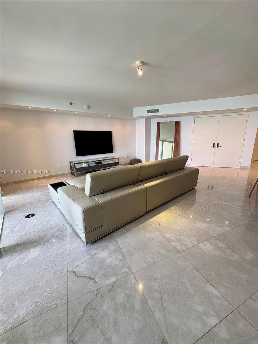 Large-format stone tile flooring, recessed cove lighting, and double-entry doors