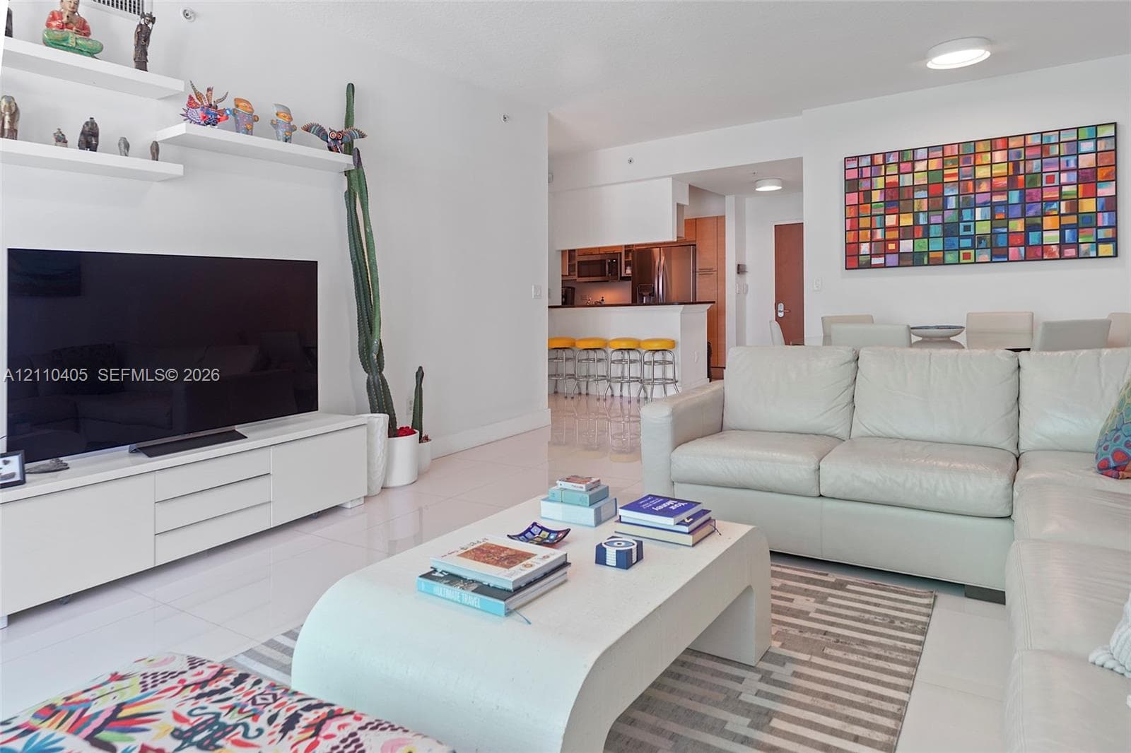 Open-concept living space featuring high-gloss tile flooring, white built-in cabinetry, and tiered wall-mounted shelving