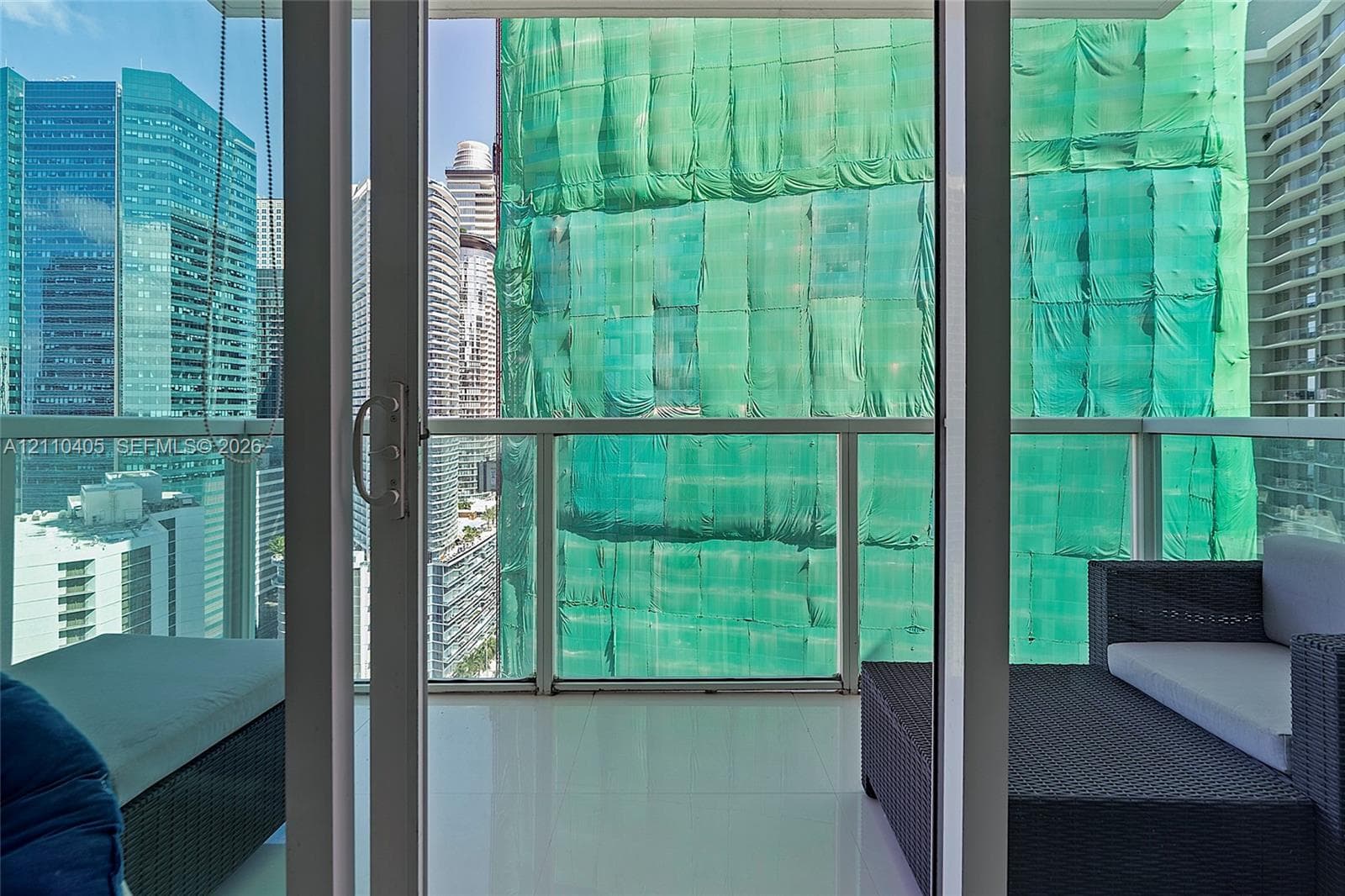 Covered balcony featuring glass railing panels, light-toned tile flooring, and sliding glass door access