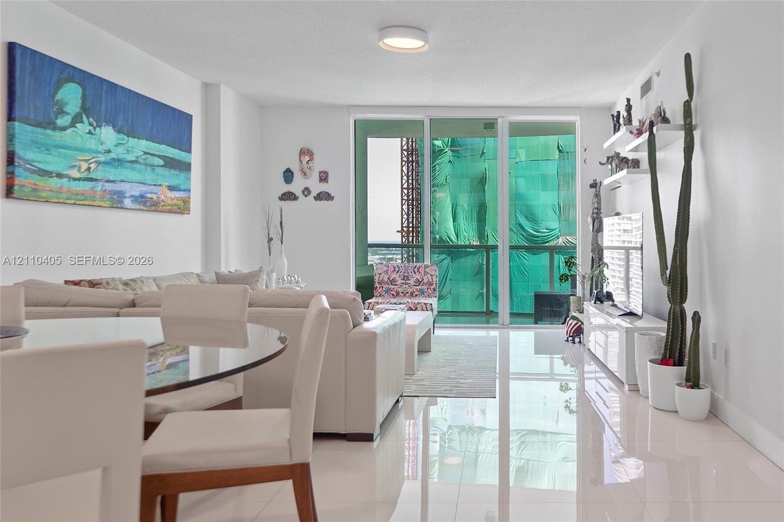 Living area featuring polished tile flooring, floor-to-ceiling glass sliding doors, and white built-in wall shelving