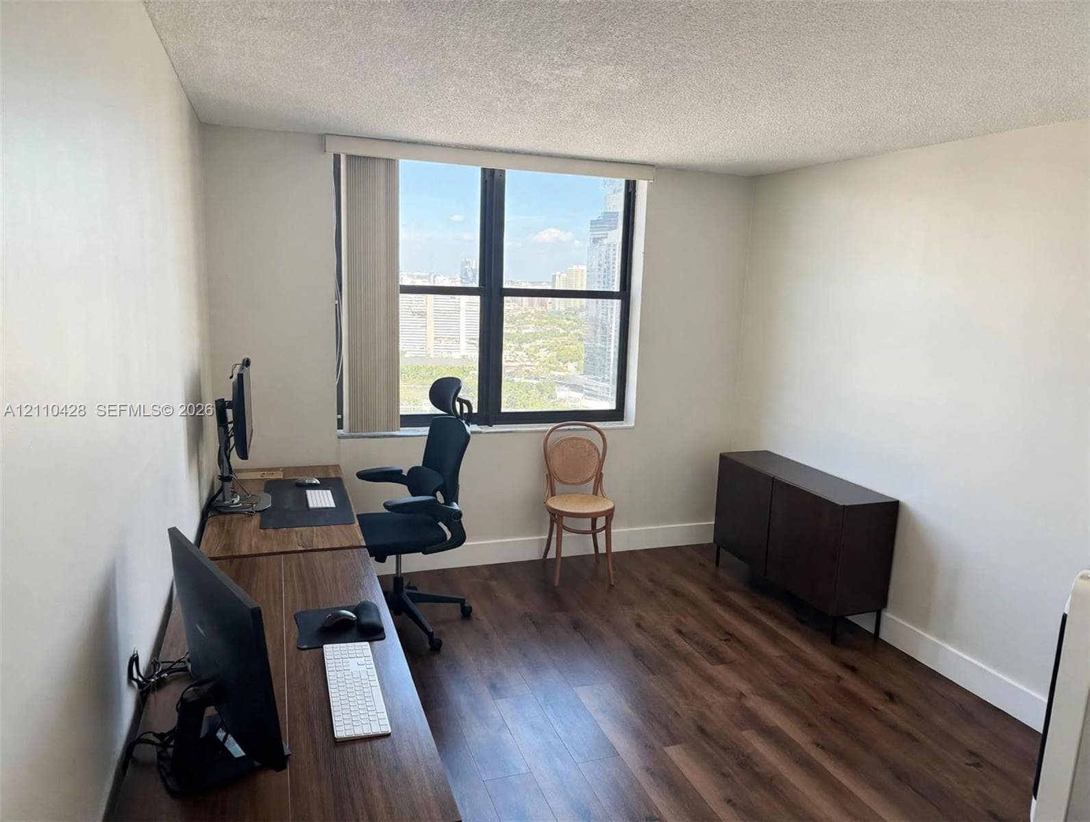 Multi-pane window with vertical blinds, wood-finish flooring, and painted interior walls