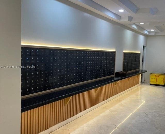 Mail center featuring integrated metal mailboxes, stone-surfaced counter, vertical wood-slat detailing, recessed lighting, and tile flooring