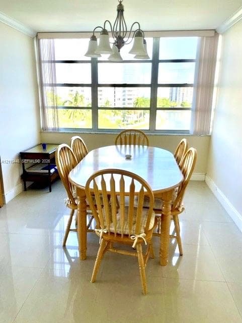 Dining area featuring large-format tile flooring, multi-pane floor-to-ceiling windows, and a multi-arm overhead light fixture with glass shades