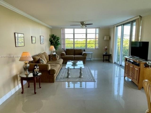 Large living area featuring polished tile flooring, crown molding, a central ceiling fan, expansive multi-panel windows, and sliding glass doors