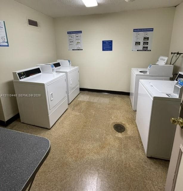Laundry room featuring dual sets of white top-load washers and front-load dryers, resilient tile flooring, and overhead flush-mount lighting
