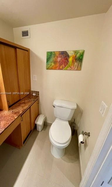 Built-in wood cabinetry with stone-finish countertop, dual-door storage, and a white porcelain toilet