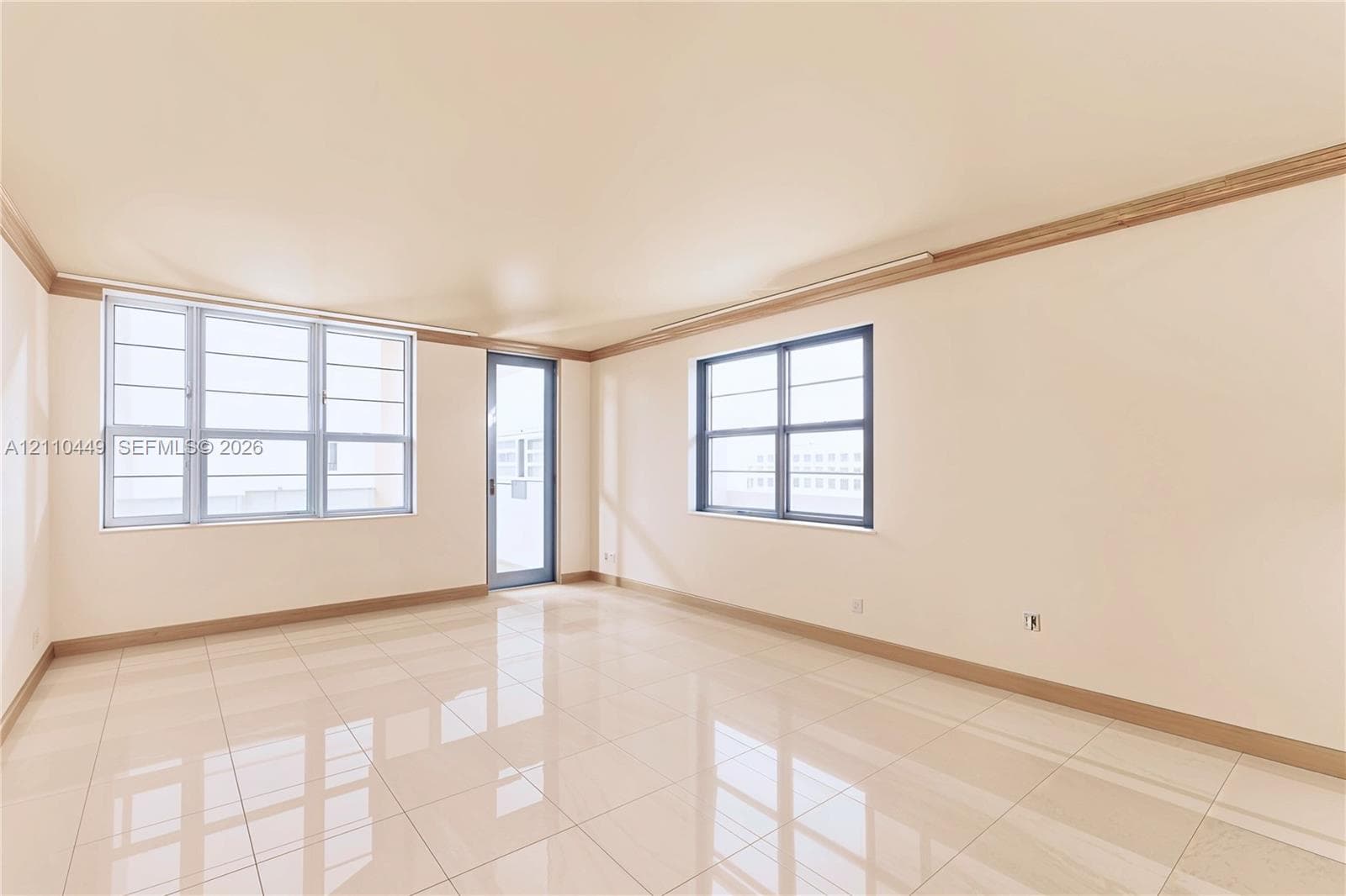 Polished tile flooring, crown molding, and large windows with integrated grid patterns, including a glass-panel door