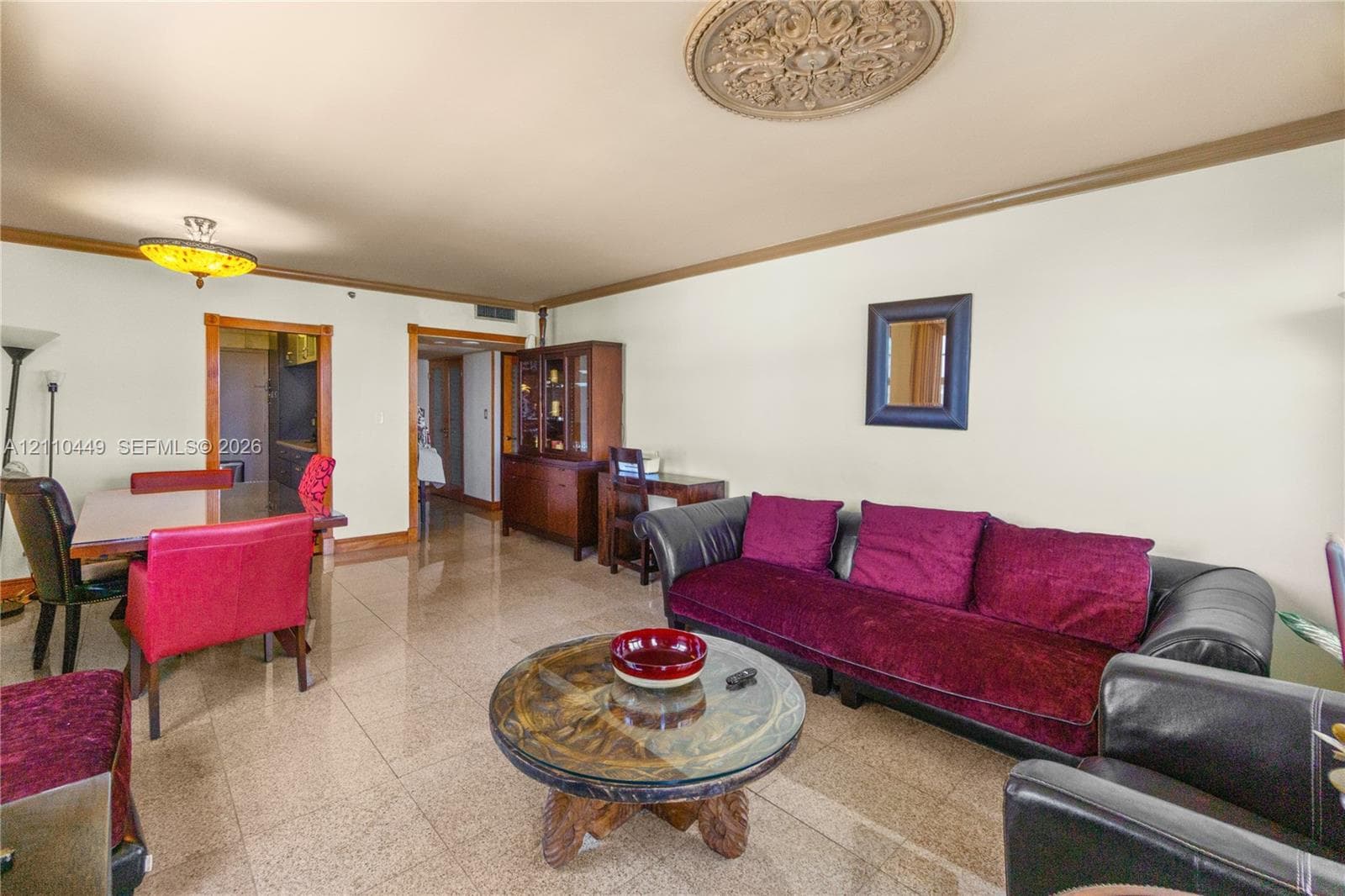 Polished stone flooring, intricate ceiling medallion, recessed tray ceiling detailing, and built-in decorative crown molding