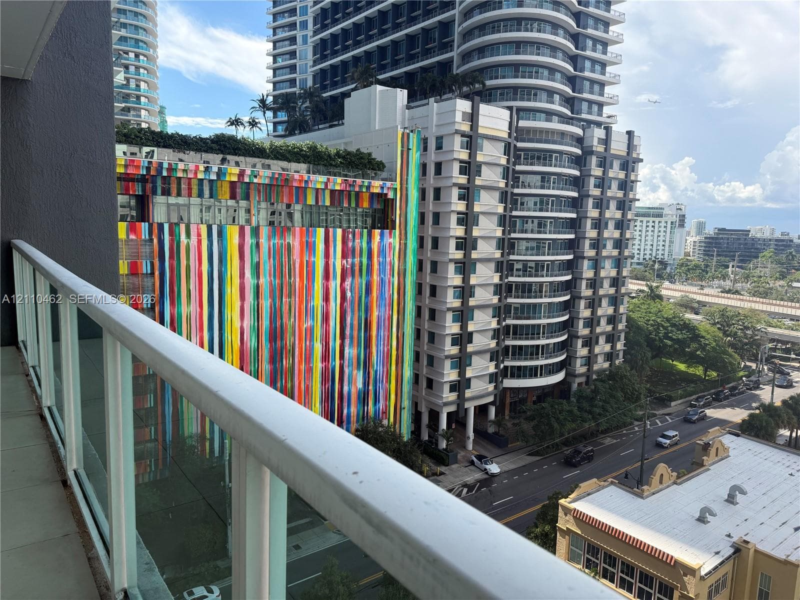 Private balcony featuring a white aluminum railing, tile flooring, and urban cityscape exposure