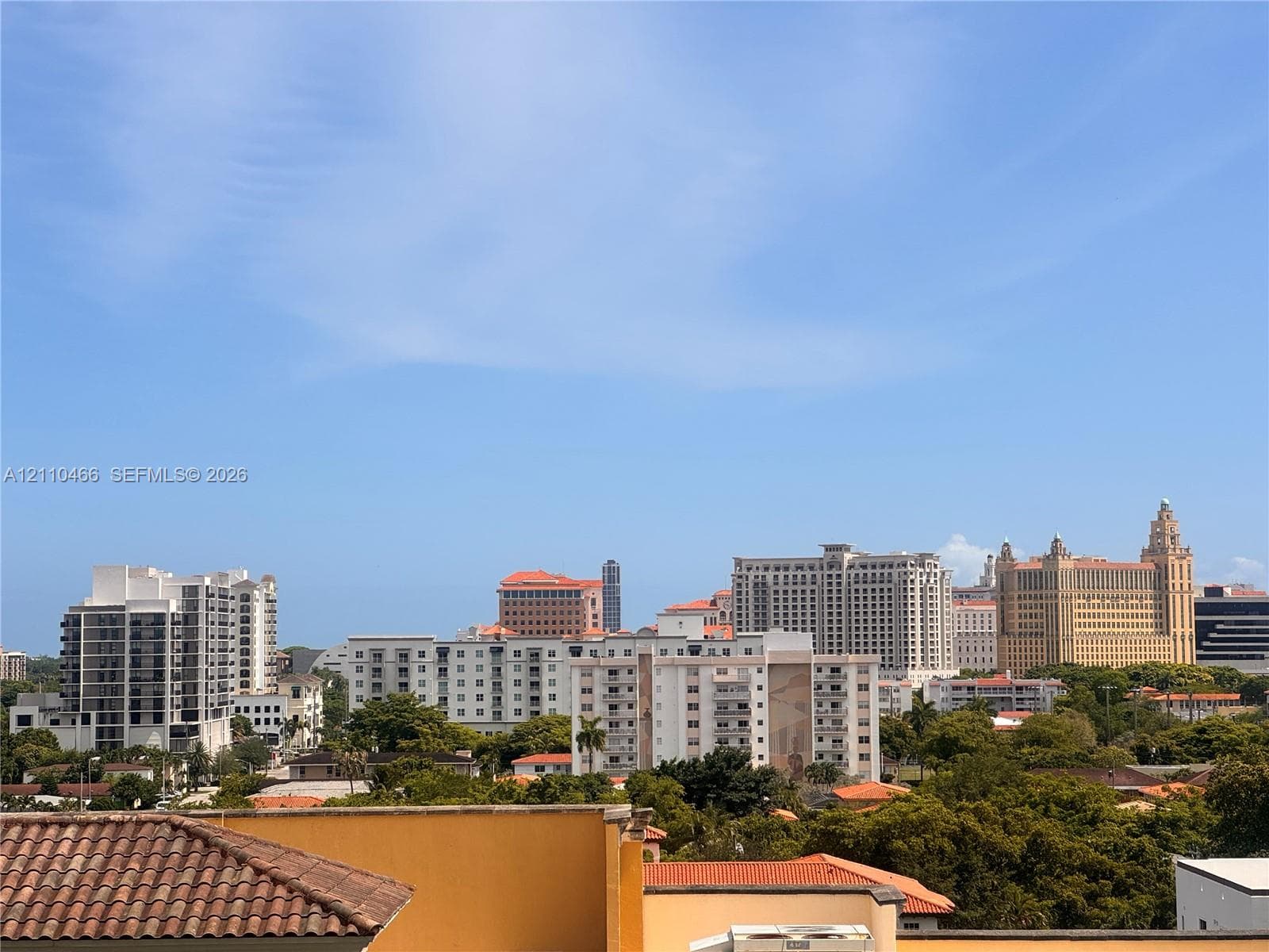 Elevated vantage point showcasing the urban cityscape, featuring mid-rise and high-rise architecture, terracotta roof tiling, and mature tree canopies