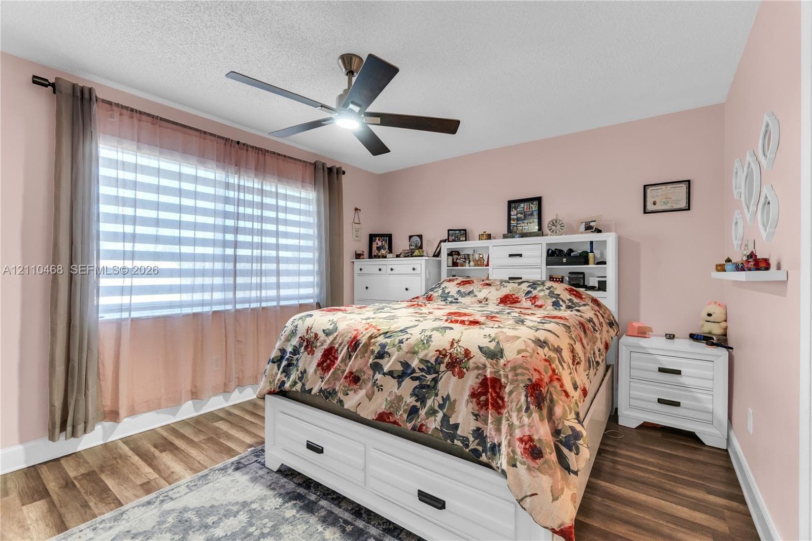 Wood-finish flooring, multi-pane window, and a central ceiling fan with integrated lighting