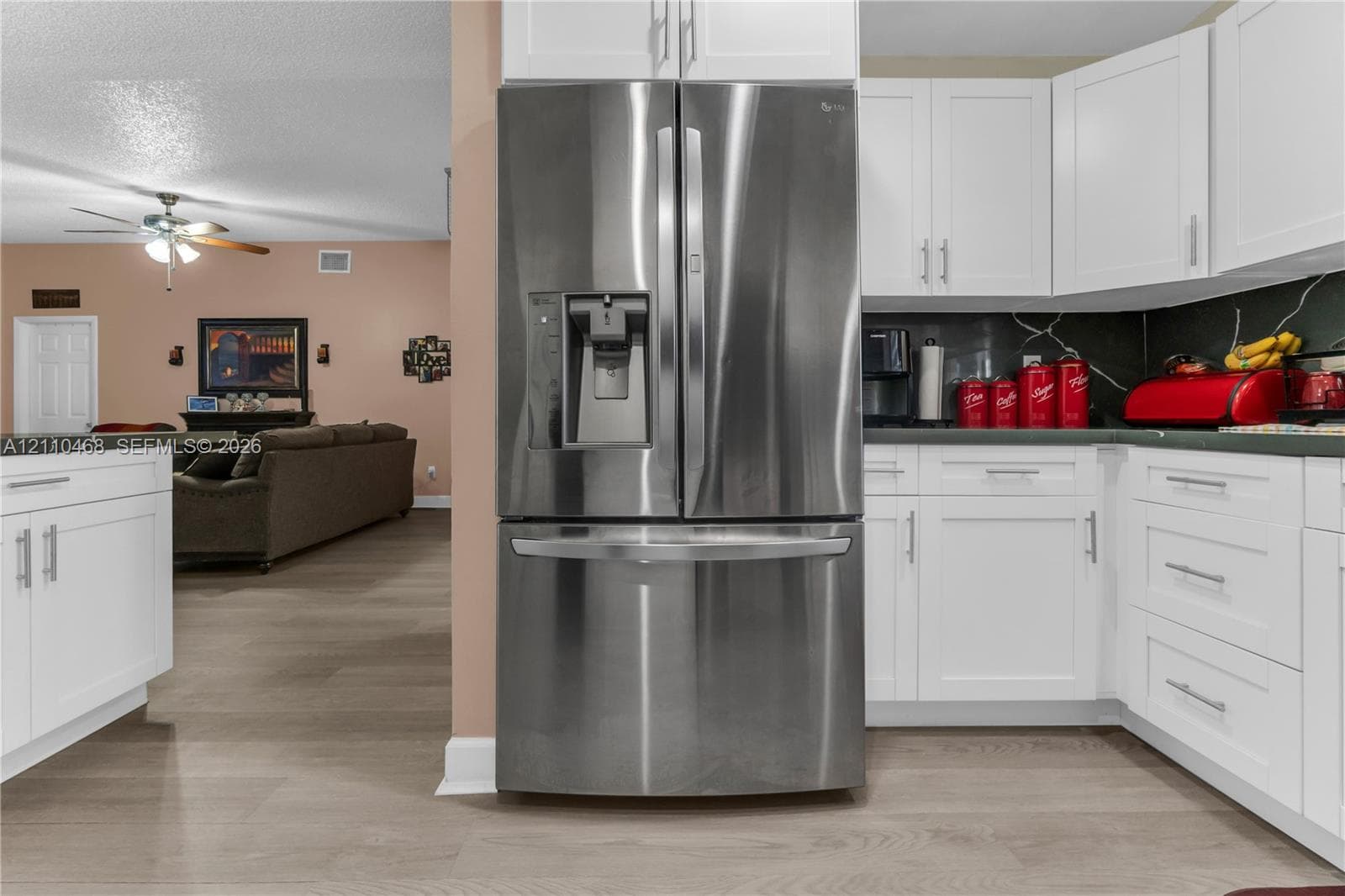 Kitchen featuring white shaker-style cabinetry, stainless steel French-door refrigerator, and wood-finish flooring